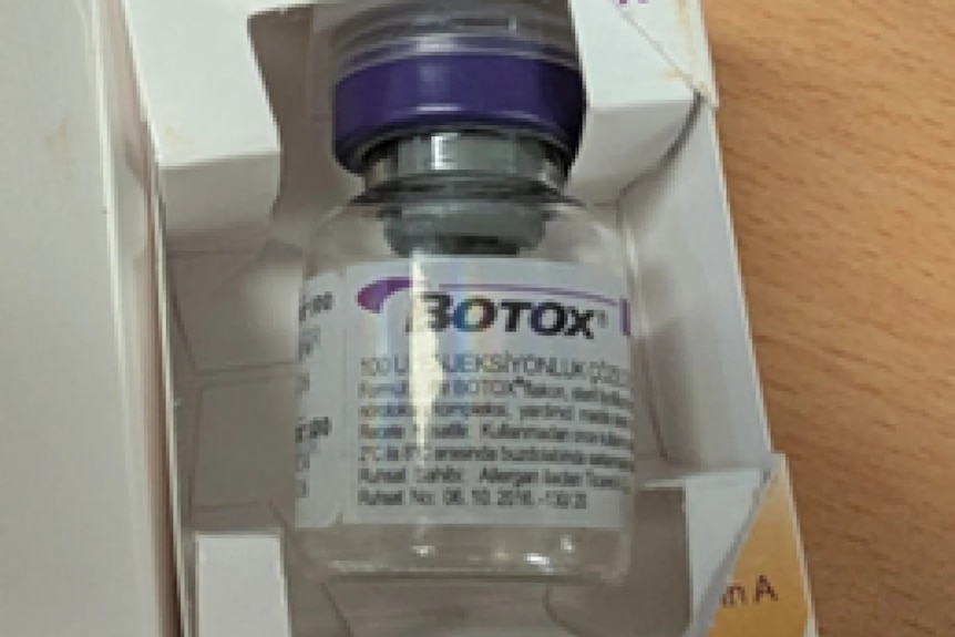 A small, clear vile in a white packaged box with a white 'BOTOX' label and purple screw cap lid