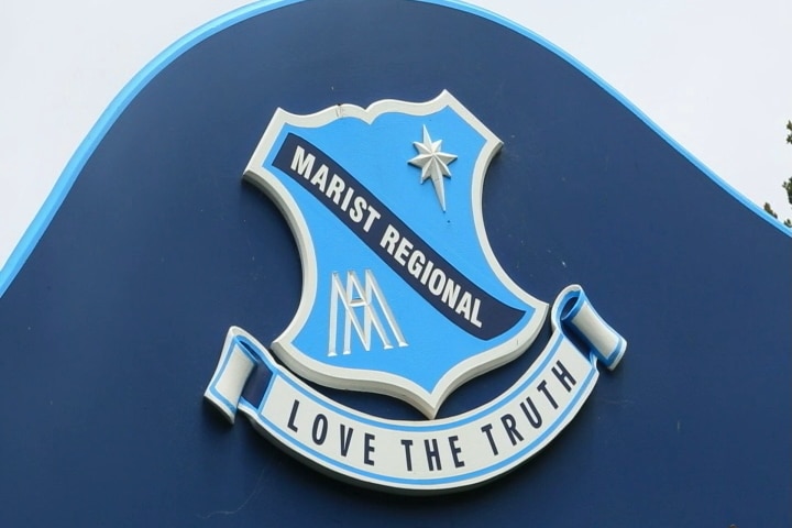 The emblem for Marist Regional College on a sign at the front of the school.
