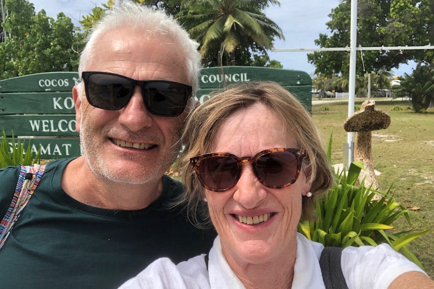 A woman takes a selfie with a man, both wearing sunglasses