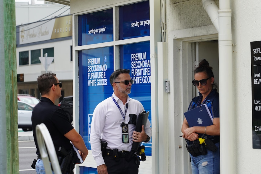 Three plain-clothes police out the front of the Serving Our People buildings.