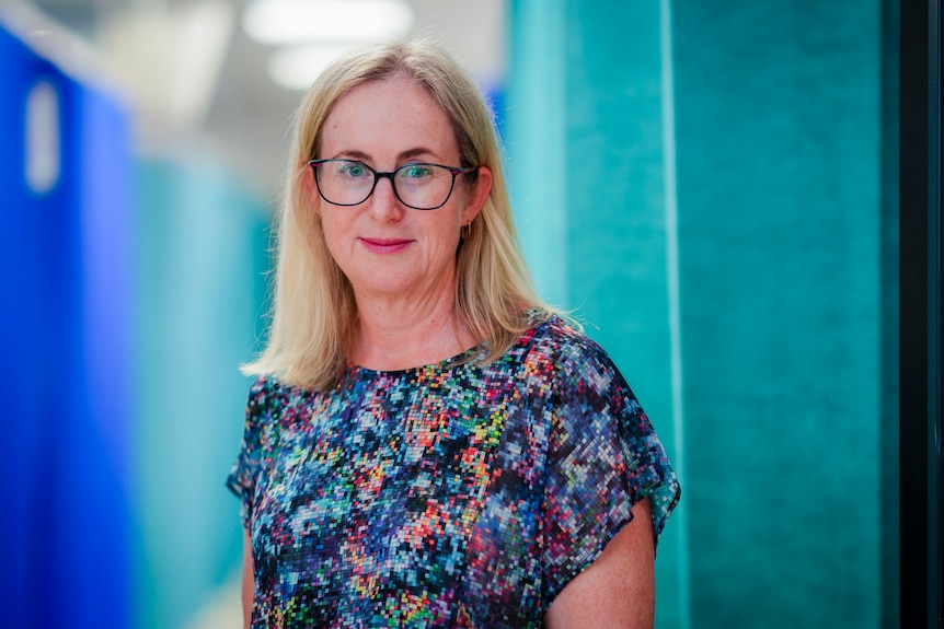 Jocelyn Howell standing in a hospital with blue curtains behind her