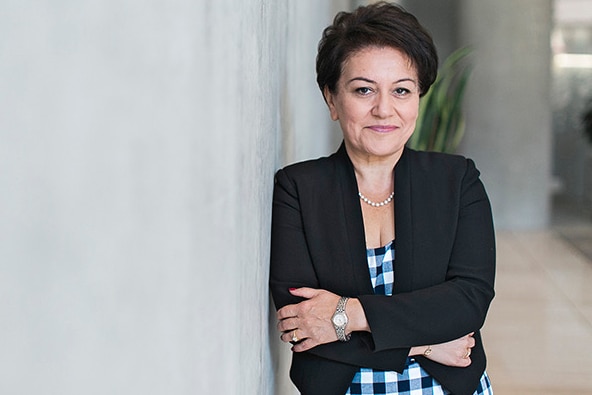 Former AQC CEO crosses arms, leaning against a wall wearing a black blazer. 
