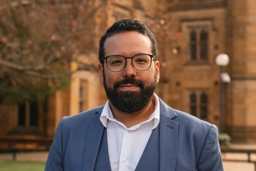 Alberto Escobar wears a suit and glasses