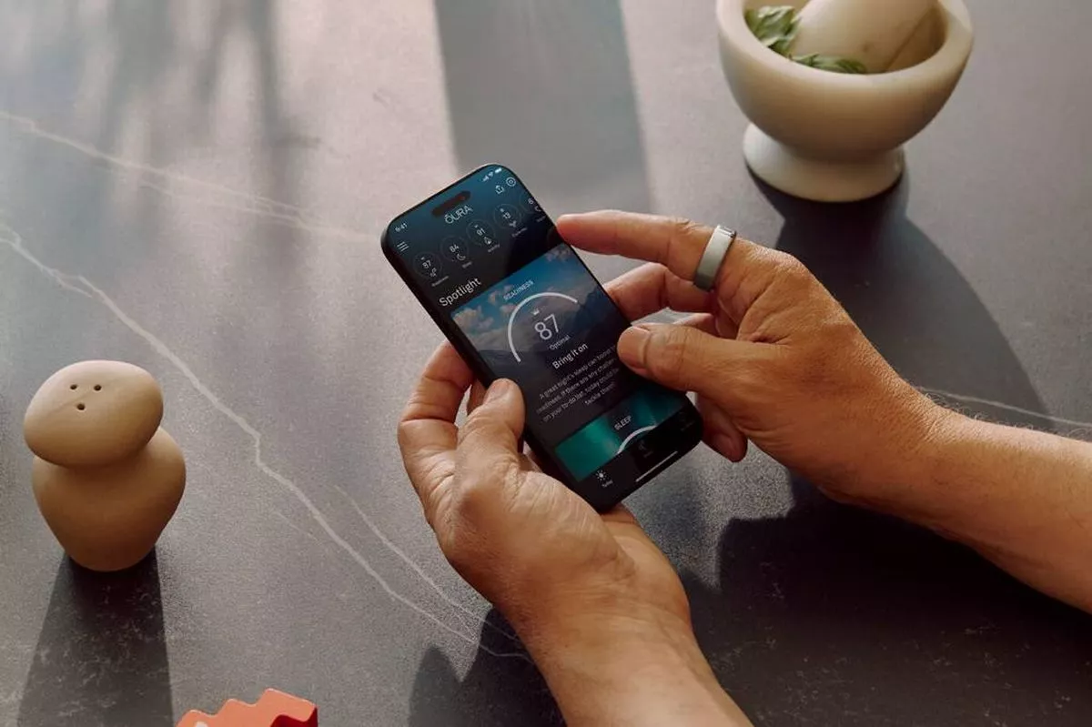 An individual holding a smartphone in their hands, with a mortar and pestle, and a pepper shaker visible in the background.