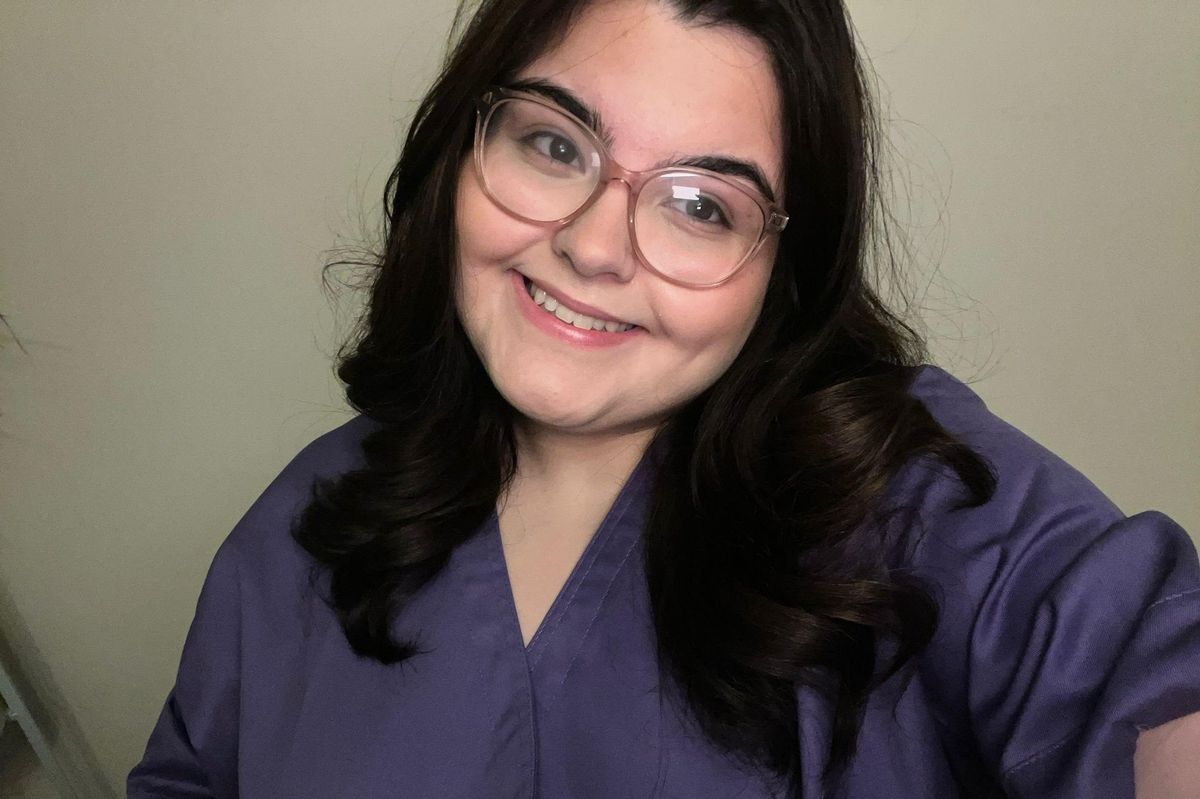 A smiling young woman with dark hair and a dark blue shirt