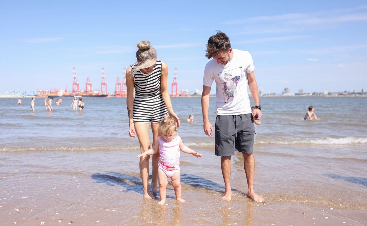 The water is calm, and in the distance, there are several ships or structures visible on the horizon.