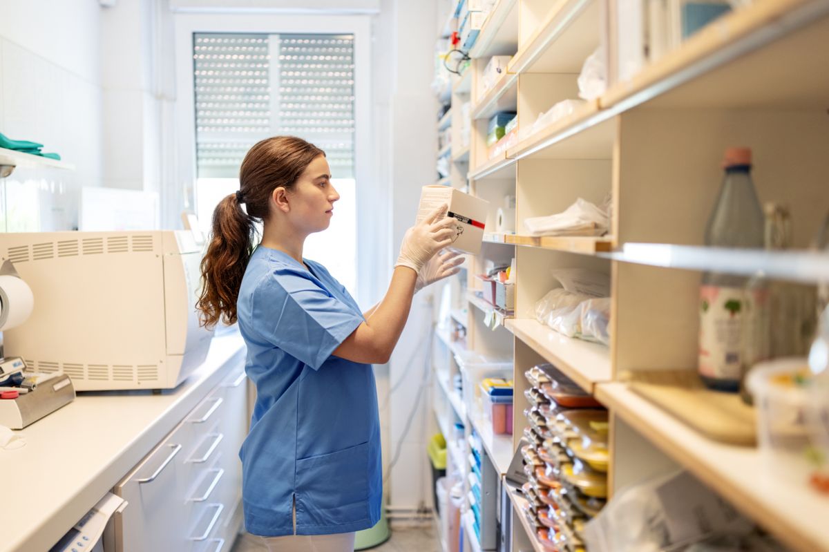 Young woman dental assistant reviewing medicine in the dentist office's pharmacy room where all medicine is stored