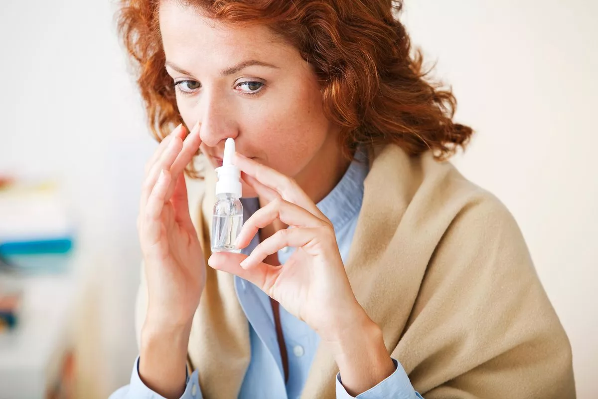 Woman using nose spray - stock photo