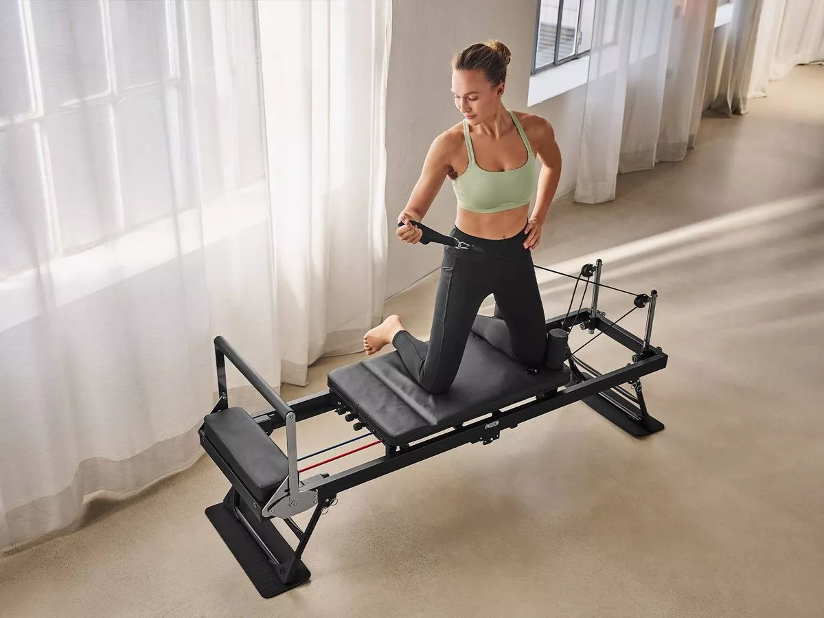 A woman using a Reformer Pilates machine 