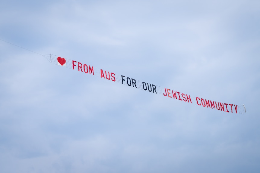 a banner flown over the sky flown over during bondi memorial reading from aus for our jewiush community