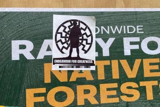 A National Socialist Network sticker stuck on top of a forest protest poster. The NSN sticker reads "Endeavour for greatness".
