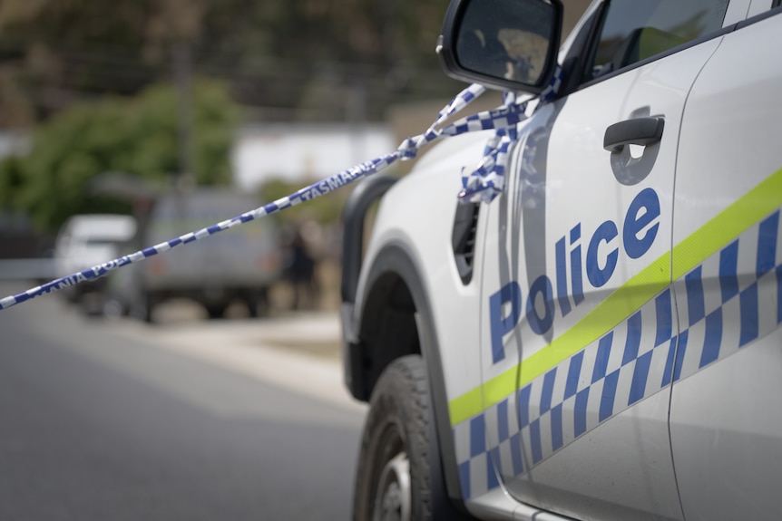 Police tape strung from a van's rear vision mirror at the scene of a shooting.