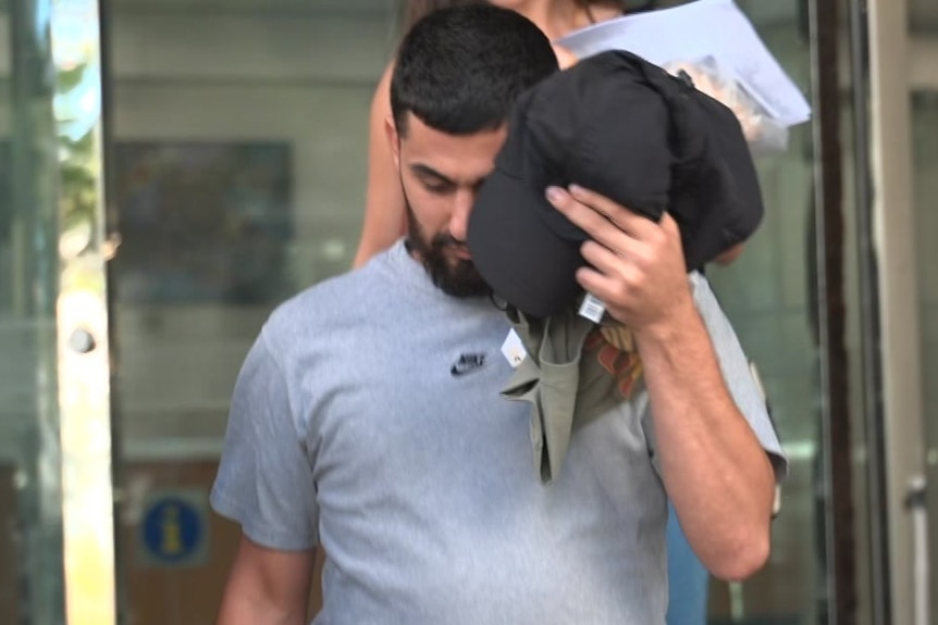 Ahmad El Ahmad walks down court steps covering his face.