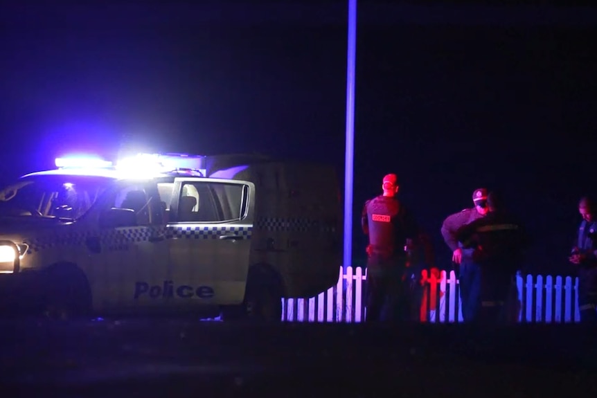 Police officers standing next to a police vehicle at night time