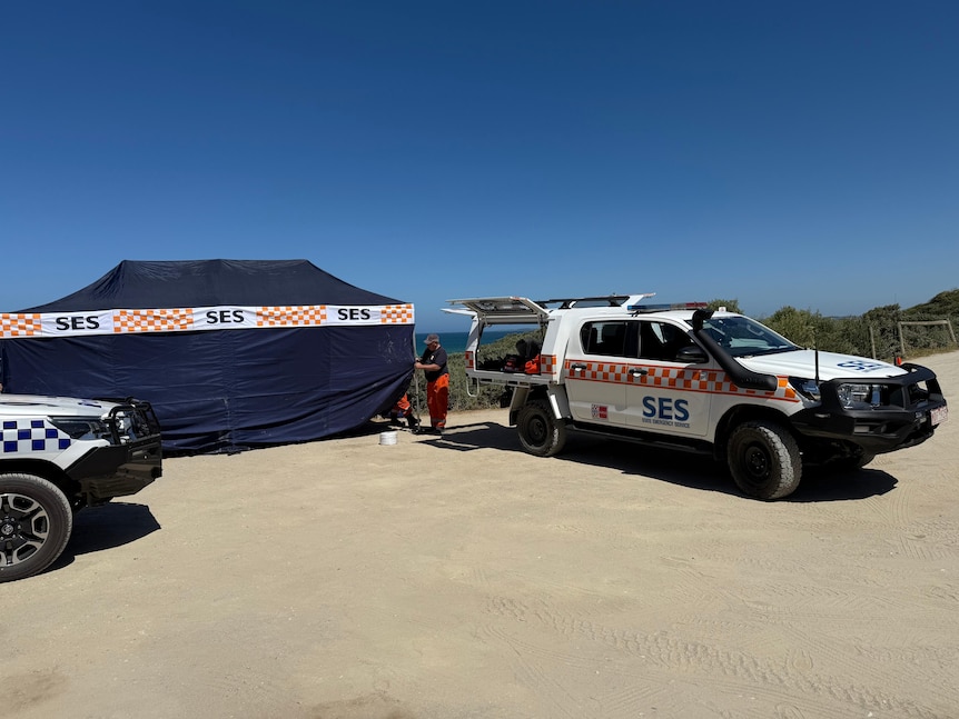 A photo of a navy tent that says "SES", next to an SES vehicle with a blue sky in the background