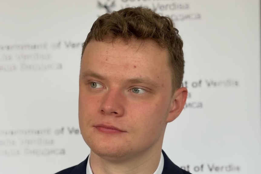 A young looking white male looking to the left of screen with a neutral expression