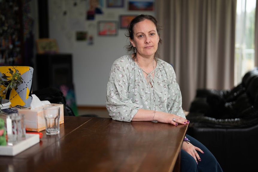A mother sitting in her living room looking at the camera.