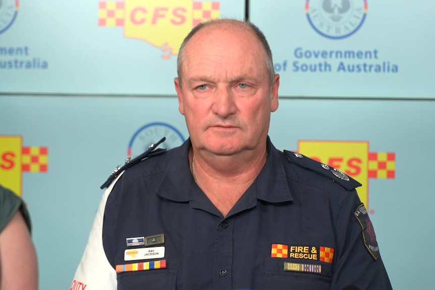 Ray Jackson is dressed in a CFS uniform as he speaks in front of a backdrop with the CFS logo