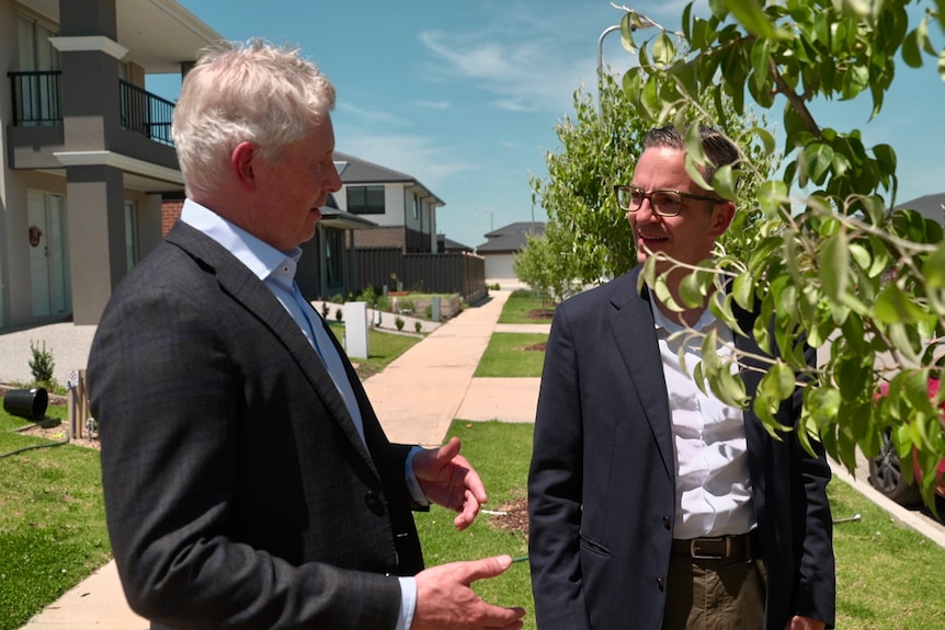 Two men standing in a suburban street talking