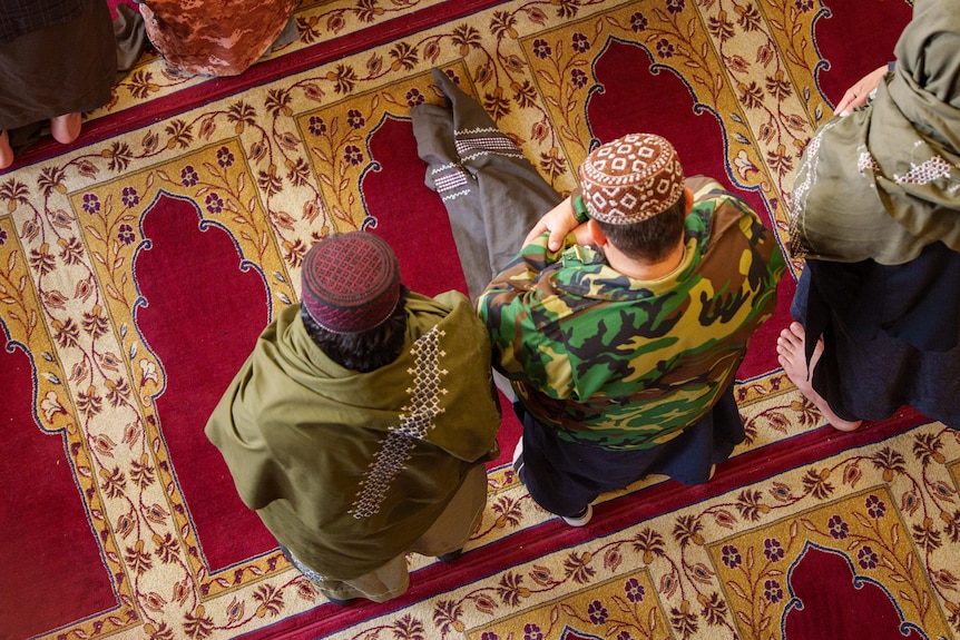Two Afghans bow their heads while sitting in a mosque in Kabul.