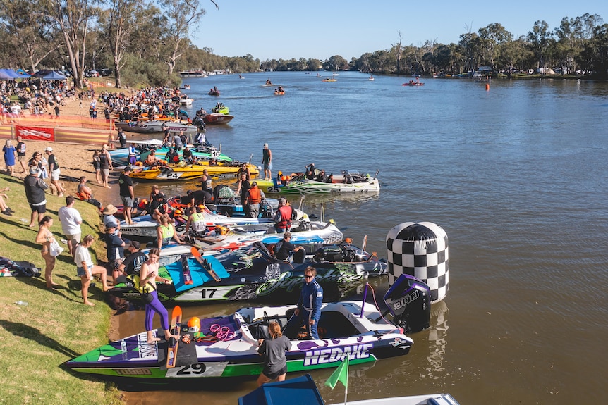 Ski boats at a riverside, with some boats in the background on the water