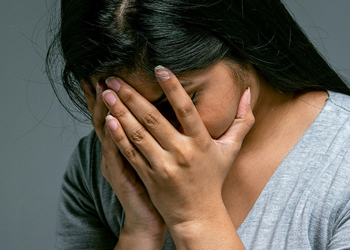 Woman covering her face in distress, representing emotional impact of unprofessional things doctors have said to patients.