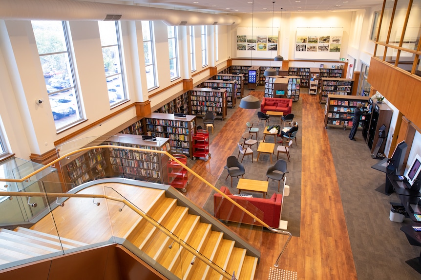 The interior of a library, showing stairs and rows of book-lined shelves