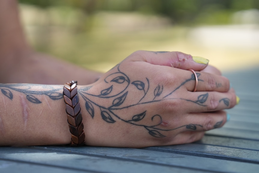 A womans holds her tattooed hands together.