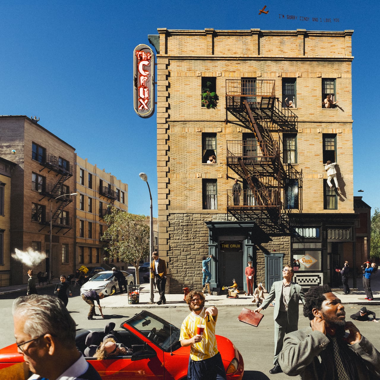 A busy street scene is shown, with a number of people seen gesticulating on a road in front of an apartment building.
