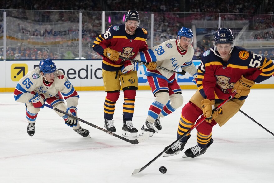 Florida Panthers center Jack Studnicka (53) skates by New York Rangers center Sam Carrick (39), Florida Panthers defenseman Uvis Balinskis (26) and New York Rangers left wing Brett Berard (65) during the second period of the NHL Winter Classic outdoor hockey game, Friday, Jan. 2, 2026, in Miami. (AP Photo/Lynne Sladky)