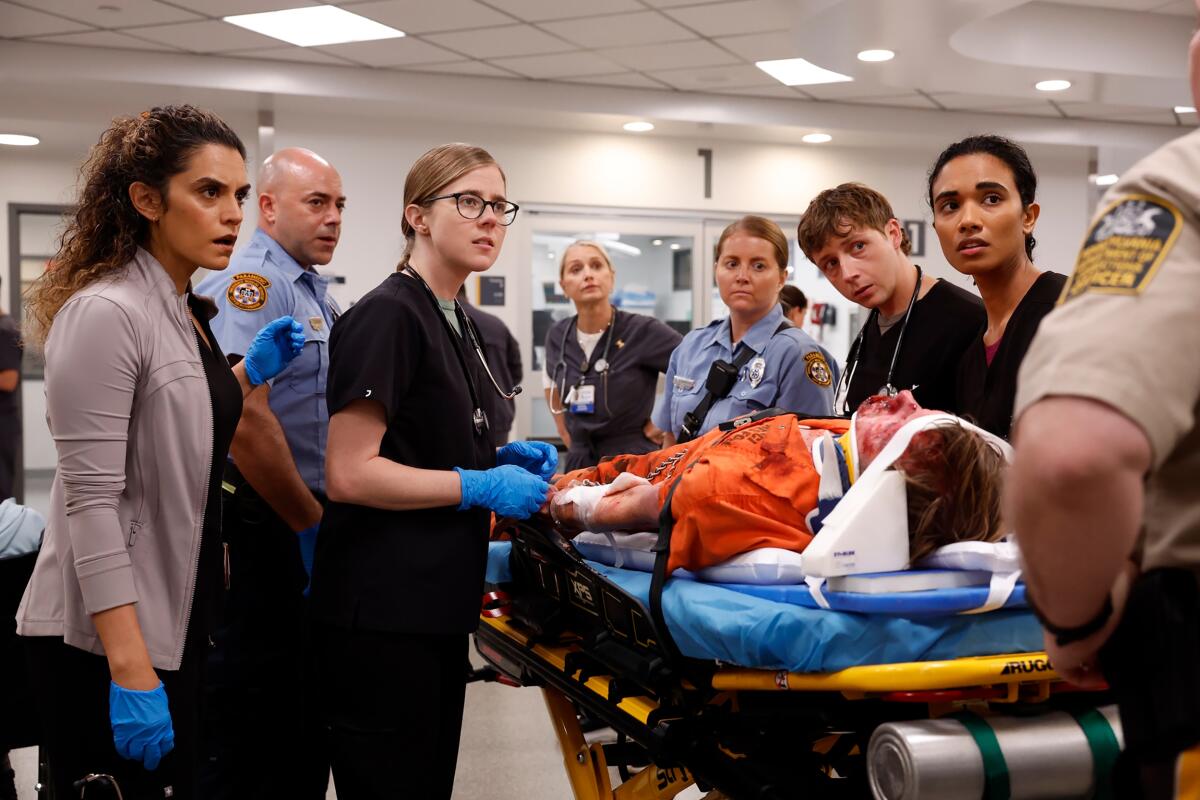 A group of medical workers stand around a patient on a guerney