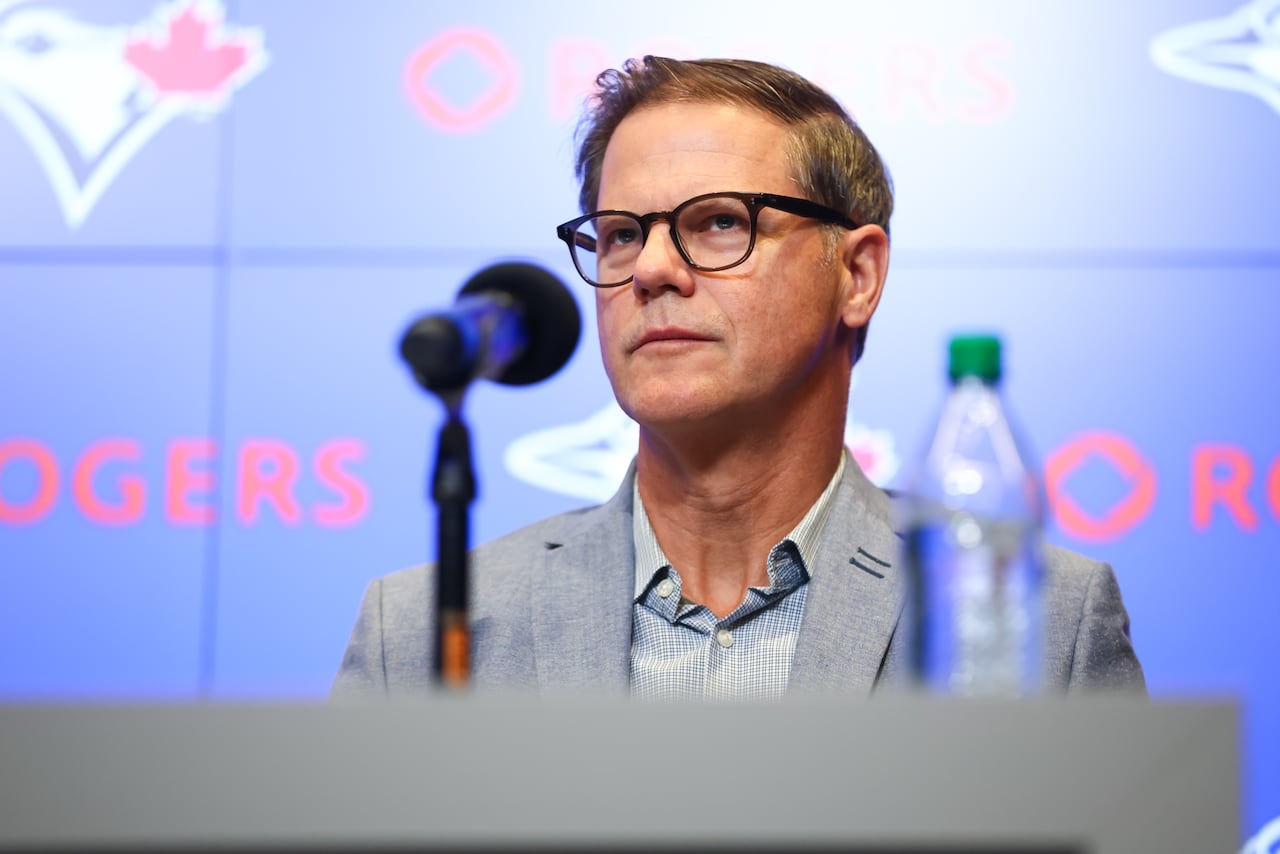 A man wearing glasses, sitting at a press conference