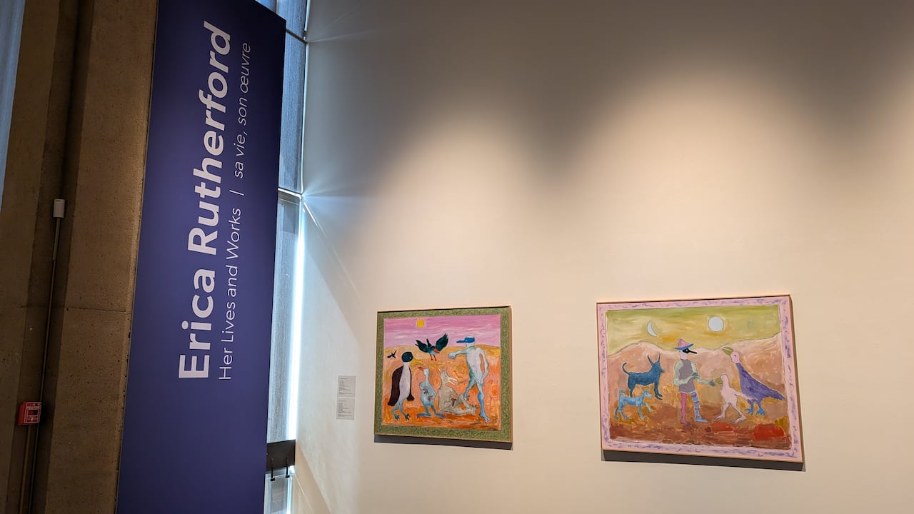 Two colourful paintings are seen on a wall next to a banner that says "Erica Rutherford Her Life and Works"