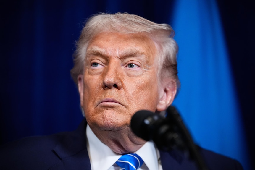 Donald Trump stands in front of a microphone.