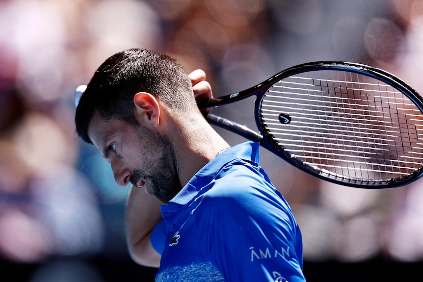 Novak Djokovic scratching his head with his racquet
