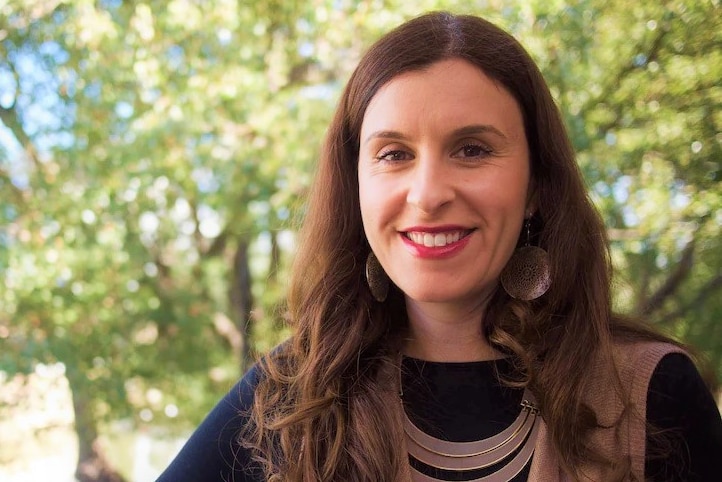 A woman wearing a necklace and smile to camera