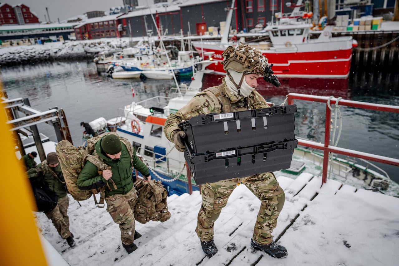 Soldiers disembark from a boat docked in a harbor.