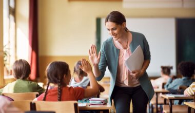 Happy elementary school teacher giving high-five to her student during class in the classroom.