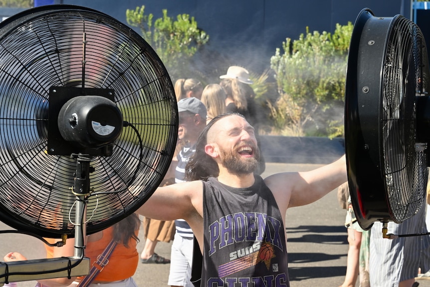 A man cools down in front of a water mister at Melbourne Park.