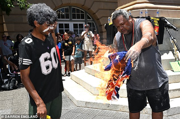 Protesters are seen burning an Australian flag during an Invasion Day rally in Brisbane, Monday, January 26, 2026. (AAP Image/Darren England) NO ARCHIVING