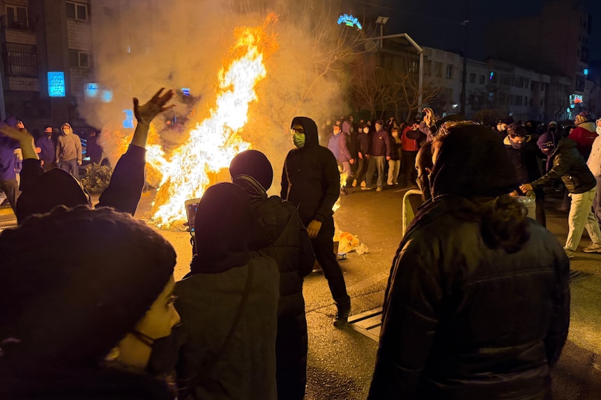 People stand around a bonfire at a protest in Tehran, Iran