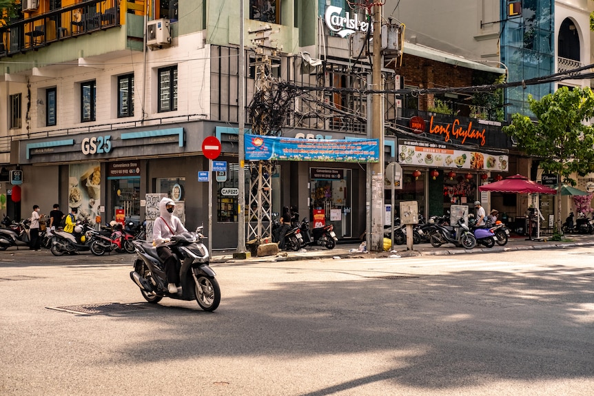A person rides a motorbike through a clear intersection on the streets of Ho Chi Minh City.