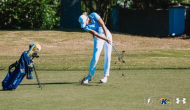 Veronika Kedronová stands smiling in front of a Kent State Golden Flashes backdrop, holding her invitation to the Augusta National Women’s Amateur. The open invitation folder displays the official Augusta National crest and printed invitation inside.