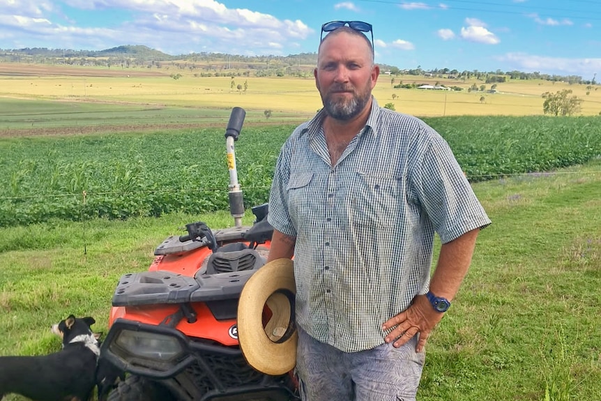 A farmer near his ATV in a paddock.