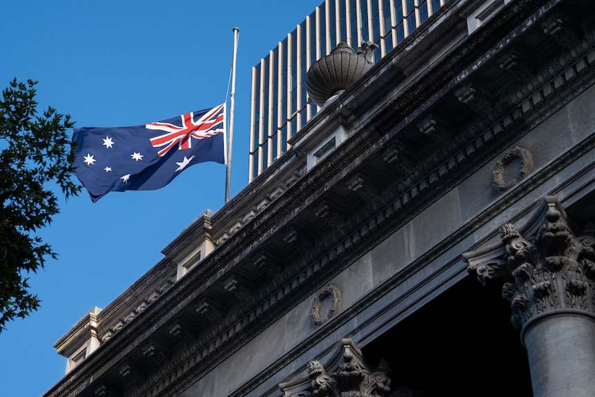 An Australian flag at half-mast on top of a stone building.