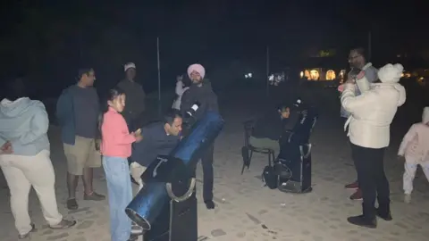 Jaspreet Singh People gather around telescoped pointed towards the sky during an astronomy workshop near Sariska Tiger Reserve in Rajasthan, India 

