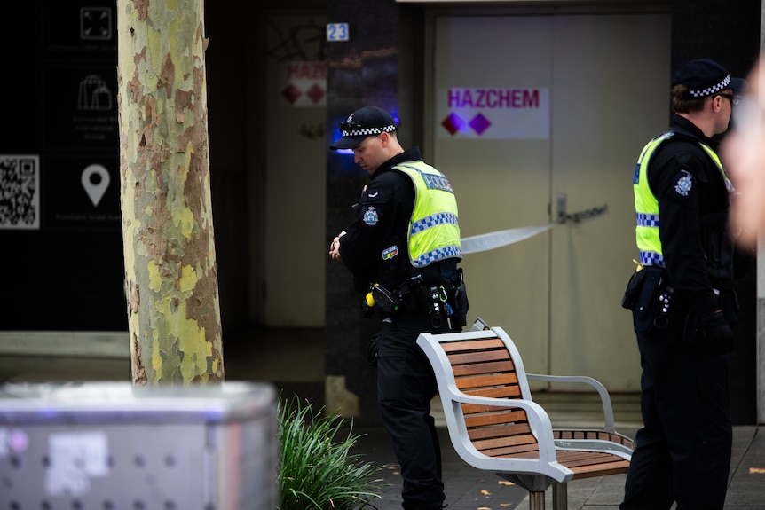 A police officer rolls out police tape.