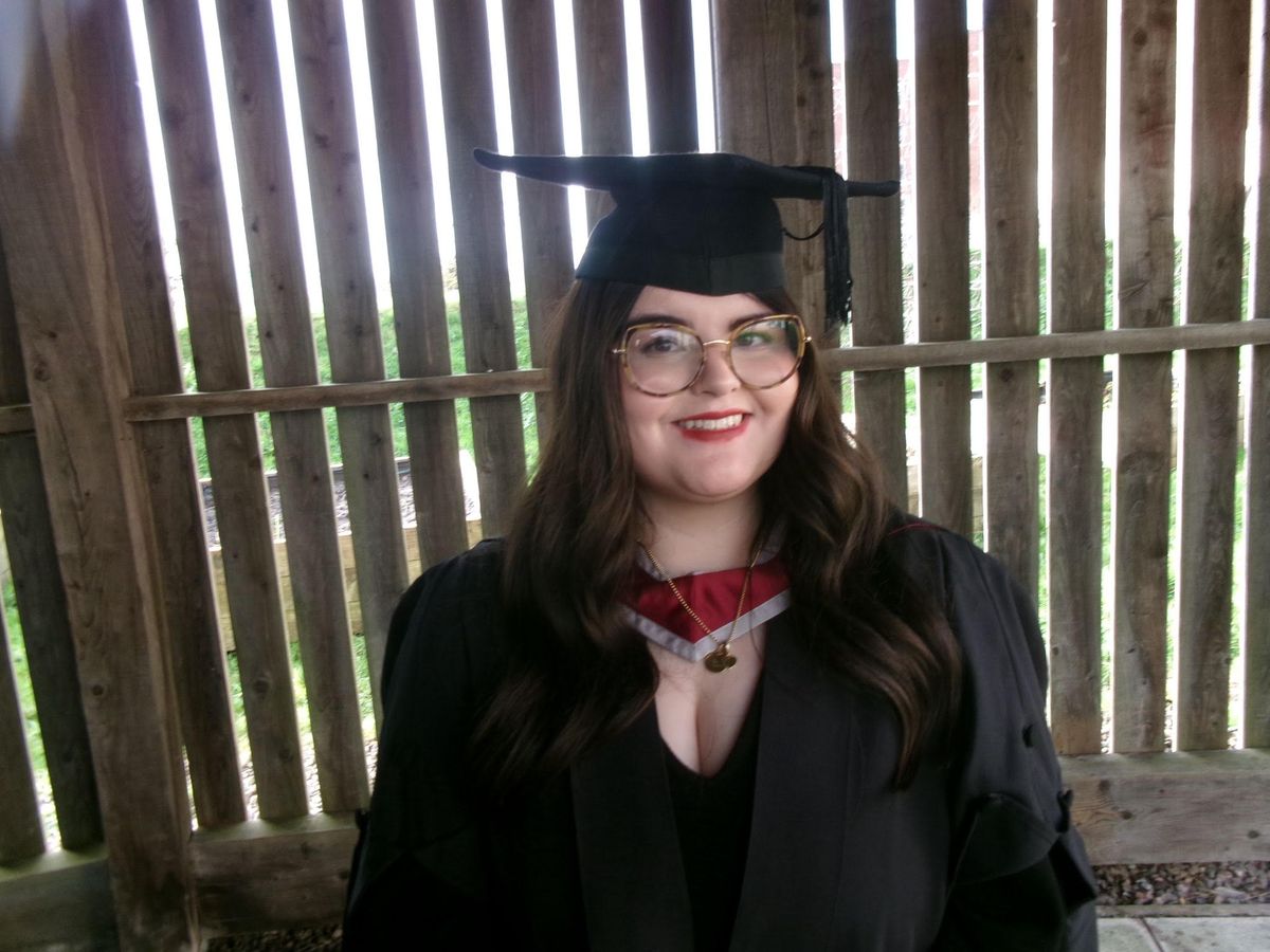 A smiling young woman in gown on her graduation day 
