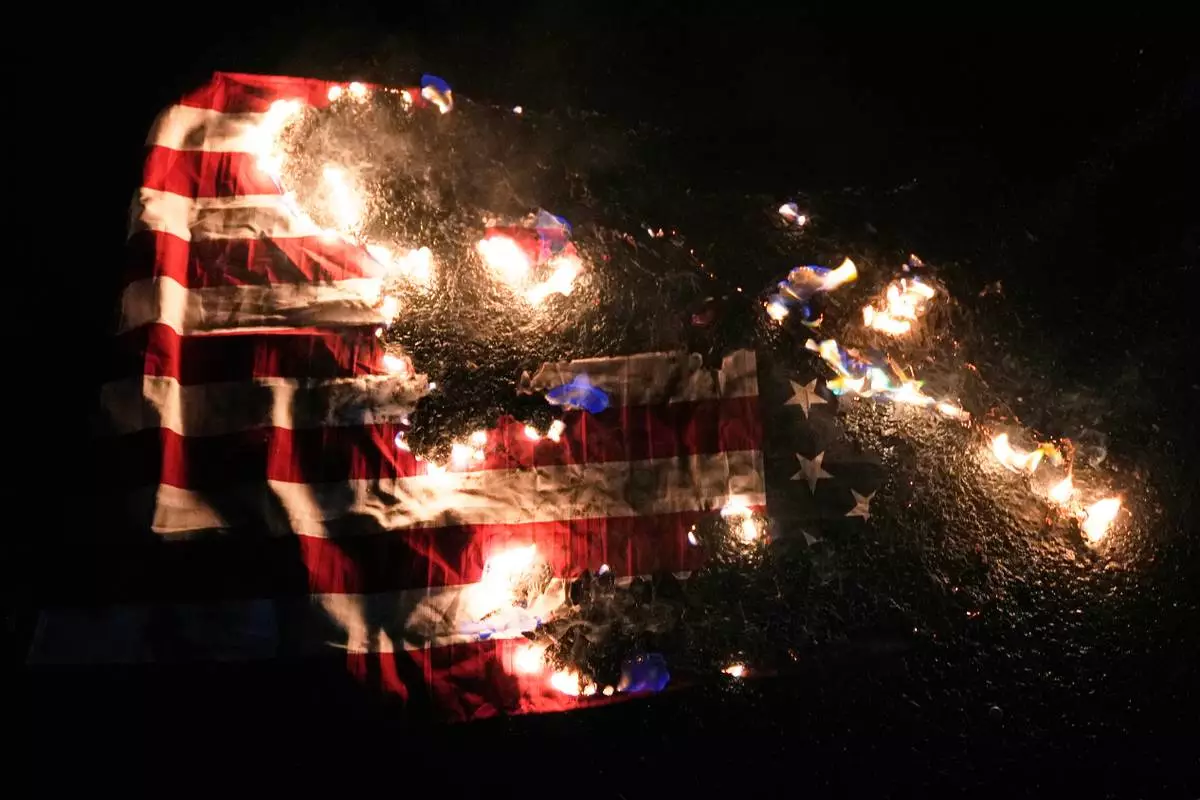 An American flag burns outside the U.S. Immigration and Customs Enforcement facility on Thursday, Jan. 8, 2026, in Portland, Ore. (AP Photo/Jenny Kane)