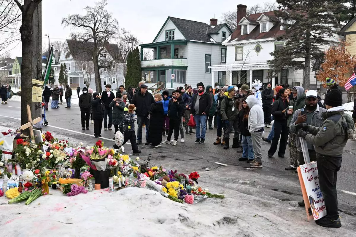 People gather around a makeshift memorial honoring the victim of a fatal shooting involving federal law enforcement agents, near the site of the shooting, Thursday, Jan. 8, 2026, in Minneapolis. (AP Photo/Tom Baker)